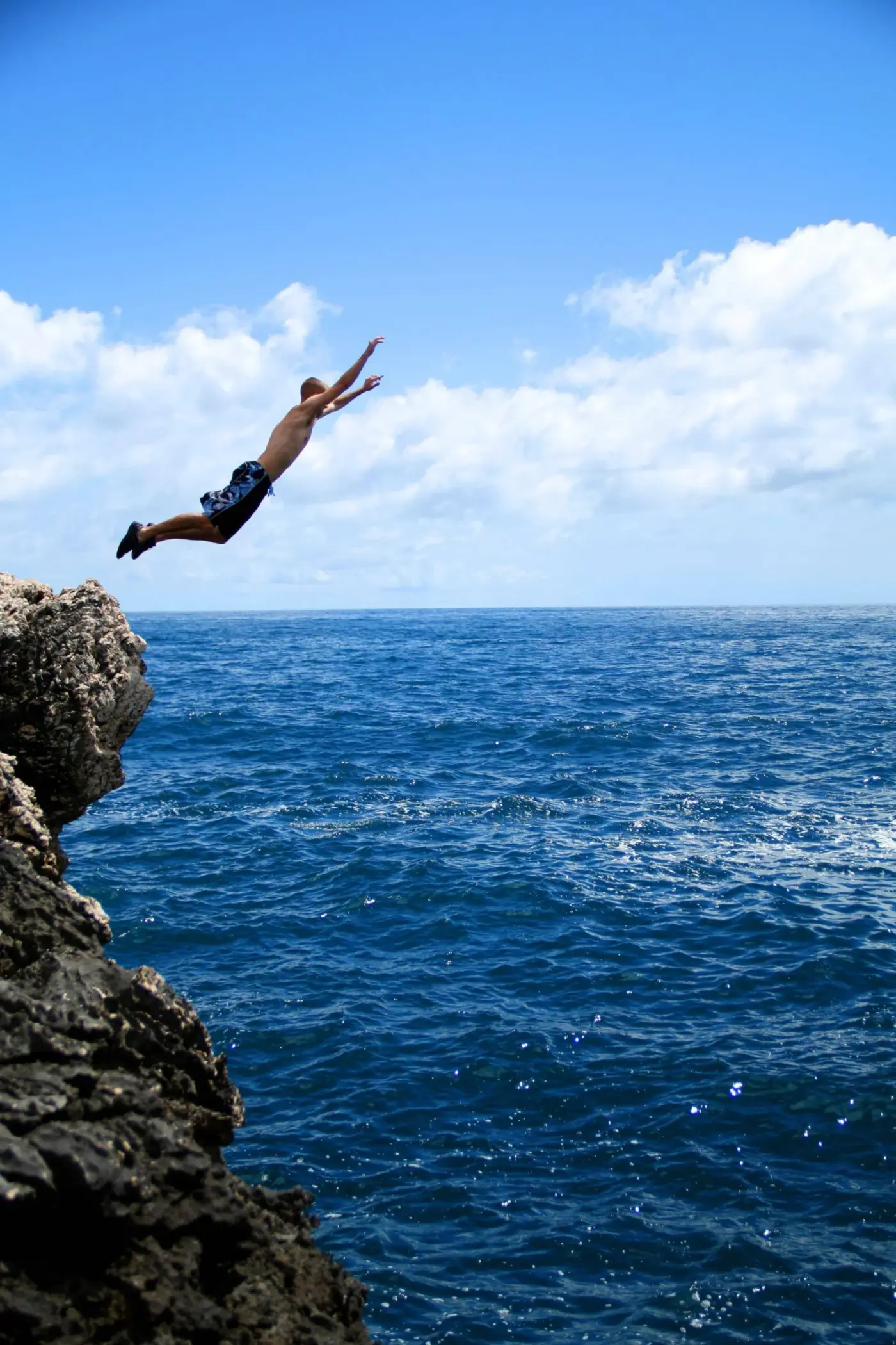 A swimmer diving from a cliff into the sea
