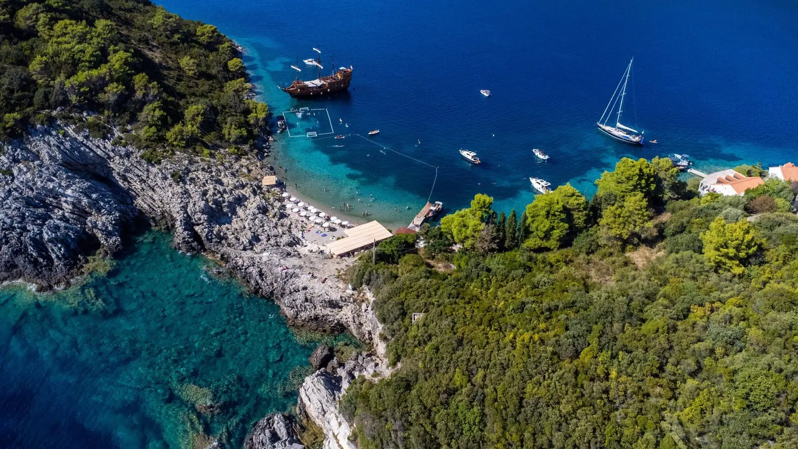 Aerial view of the bay at Priježba on Šipan with a pirate boat anchored beside the sea court